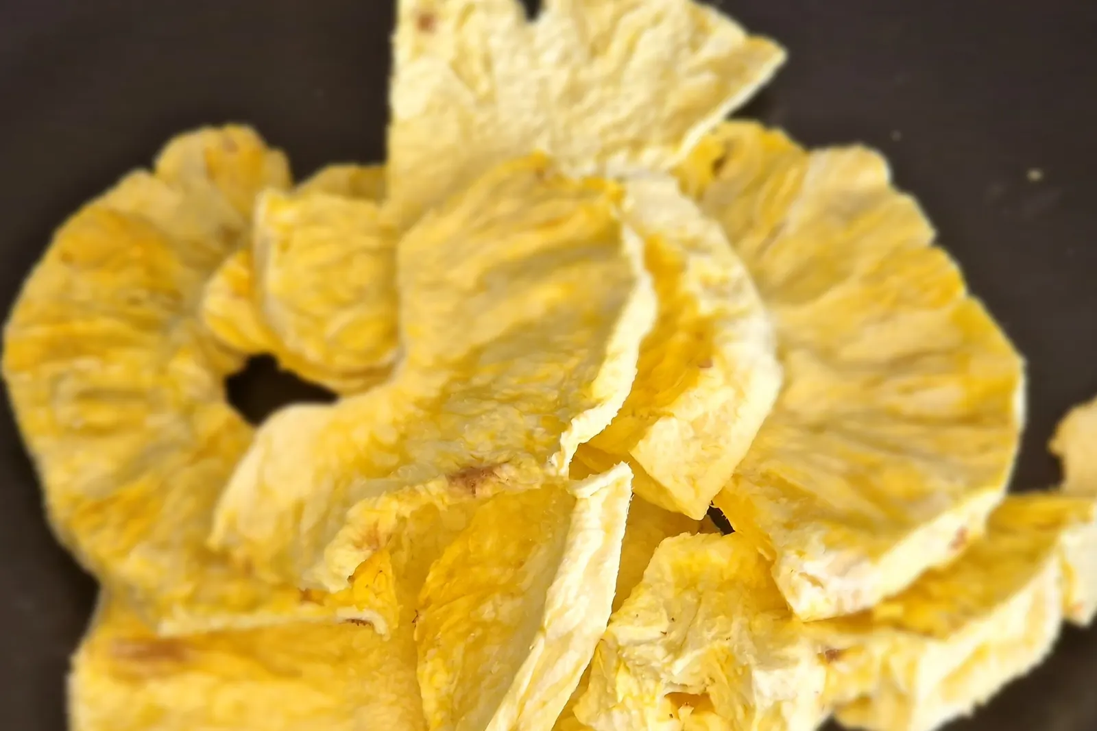 Freeze-dried pineapple slices, pale and matte, holding their full ring shape