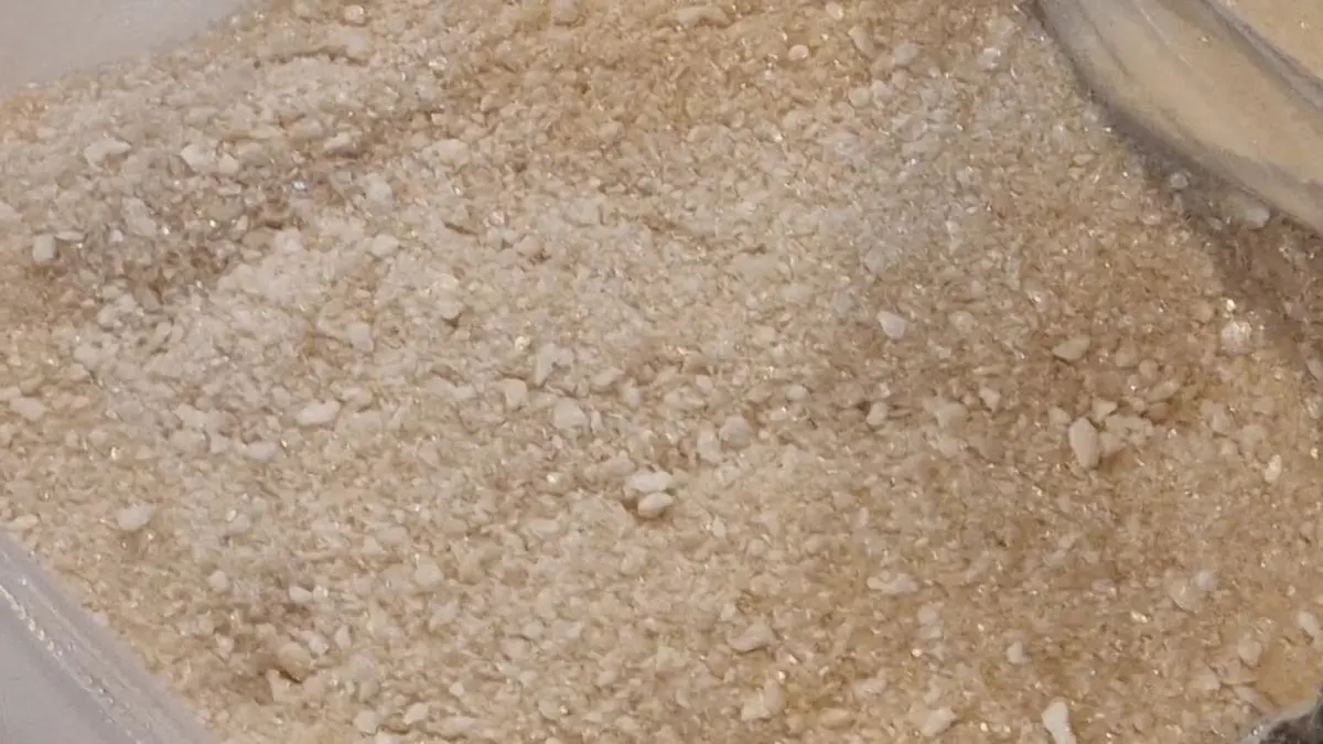Close-up of coarse freeze-dried beef broth, irregular pale-gold particles with visible porous fragments