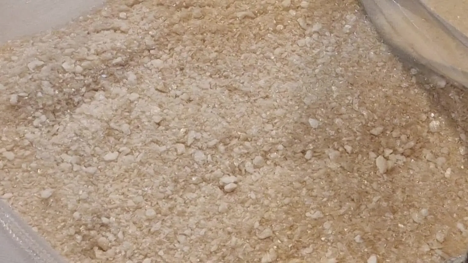 Freeze-dried beef broth in a clear barrier bag, a coarse pale-gold crush with the bag seam visible